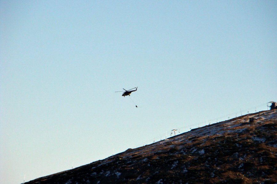 vrtulník sa ponad lanovkou vracia pre vodu na stavbu novej stanice lanovky